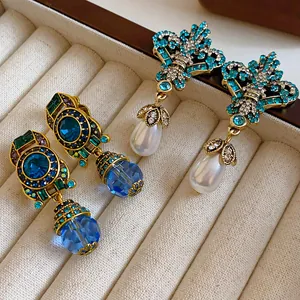 Close-up of vintage gold-tone drop earrings with blue crystals and white pearls