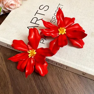 Macro detail view of large red acrylic flower earrings featuring yellow bead centers