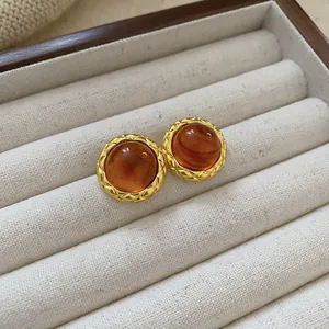 Macro view of vintage brown resin stud earrings featuring elegant gold quilted metal borders