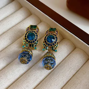 Detailed macro view of vintage gold-tone drop earrings with blue and green crystals