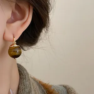 Detailed close-up showing a vintage brown tiger eye stone earring in warm Maillard style