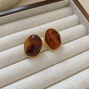 Macro detail of vintage amber oval stud earrings featuring gold twisted rope border.