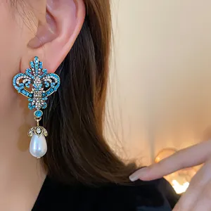 Detailed view of vintage silver needle earrings with blue rhinestones and teardrop pearl