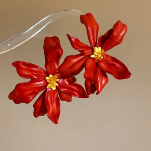 Macro view of detailed red acrylic flower petals and yellow bead centers on earrings.