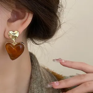Close-up detail of retro brown heart-shaped dangle earrings with a gold-tone metal finish