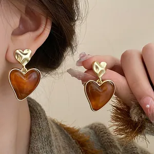 Detailed macro view of retro brown heart-shaped drop earrings with gold textured tops