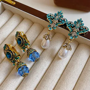 Close-up of vintage rhinestone drop earrings with blue crystal and pearls in jewelry box.