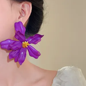 Close-up of a large purple acrylic flower earring with a yellow center worn by a model