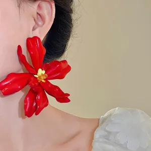 Detail shot of oversized red acrylic flower earring on model for vacation style