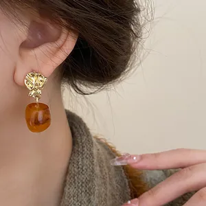 Close-up of retro Maillard style brown oval drop earrings with gold textured studs