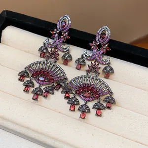 Detailed view of vintage fan-shaped earrings featuring red zircon and teardrop stones.