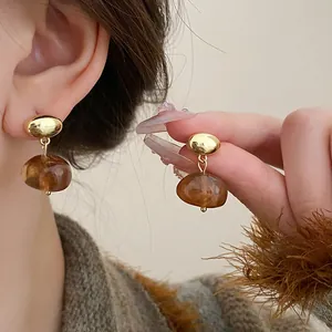 Macro shot of vintage brown oval resin drop earrings with gold-tone studs and silver needles