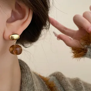 Close-up of vintage brown elliptical geometric drop earrings in Maillard style