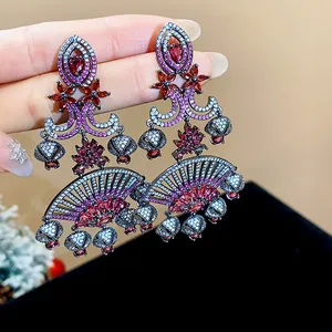 Detailed view of vintage fan-shaped earrings with red and pink zircons on silver needles.