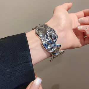 Close-up view of an irregular molten metal cuff bracelet with shiny silver finish on wrist.
