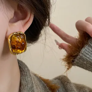 Detailed view of vintage amber-colored resin oval earring with a textured gold-tone frame