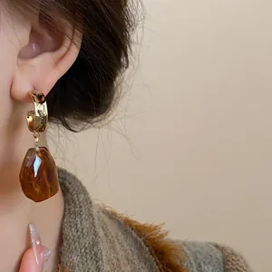 Close-up of vintage brown resin geometric drop earrings worn on ear in warm tones