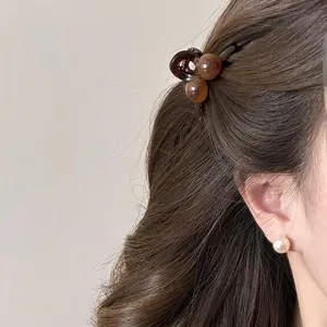 Detail of a mini brown hair claw clip with beads styled on hair for an elegant look.
