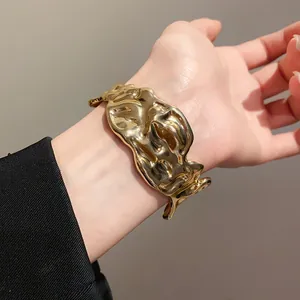 Detailed close-up showing the crumpled texture of a gold irregular metal cuff bracelet.