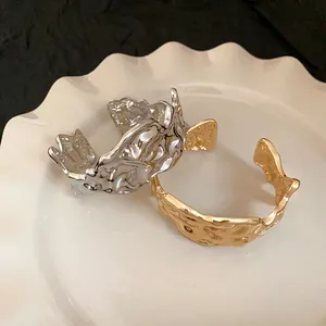 Detail shot of irregular crumpled metal cuff bracelets in gold and silver finish