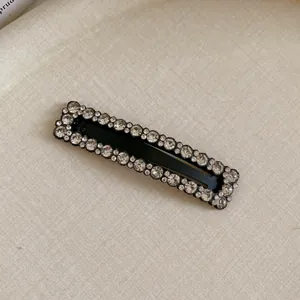 Detailed close-up of a black rectangular hair clip embellished with sparkling rhinestones