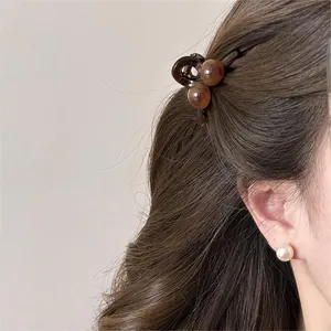 Detailed close-up showing a minimalist brown mini claw clip styled in wavy hair
