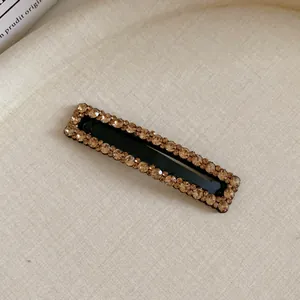Elegant rectangular hair clip with sparkling champagne rhinestones on black base.
