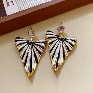 Gros plan détaillé de boucles d'oreilles triangulaires à rayures rétro avec zircons.