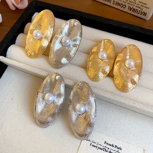 Dettaglio elegante di orecchini a perno ovali in oro e argento con perle centrali
