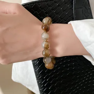 Close-up of a retro-style marbled beaded bracelet with brown swirls worn on a wrist.