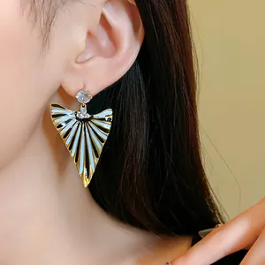 Détail de boucles d'oreilles triangulaires rétro rayées avec des pierres de zircon luxe