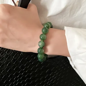 Close-up of green marble-patterned beaded bracelet on wrist with elegant white shirt
