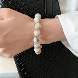 Close-up of marbled beaded bracelet on wrist with elegant lifestyle background