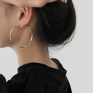Elegant side view of a large silver Mobius twisted hoop earring worn by a model.