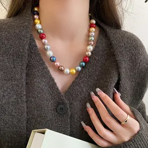 Detail shot of a vibrant colorful pearl necklace worn with a stylish brown knit cardigan