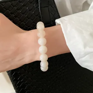 Elegant marbled white bead bracelet worn on wrist against a black woven bag background