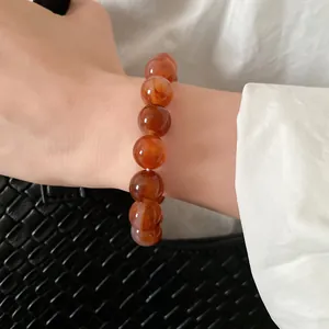 Close-up detail of an orange marbled bead bracelet worn on a female wrist