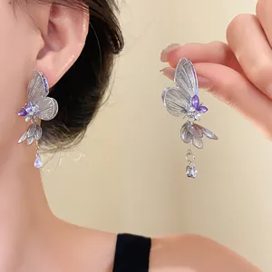 Detailed view of silver hollow butterfly drop earrings featuring purple crystal accents