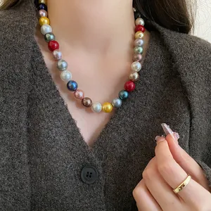 Close-up of a colorful round pearl necklace on a model wearing a brown cardigan.