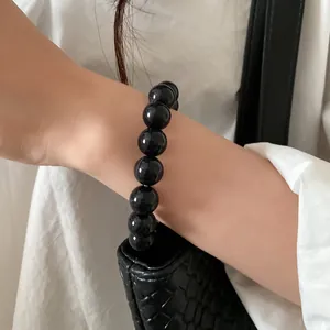 Close-up view of a minimalist glossy black bead bracelet worn on a female wrist