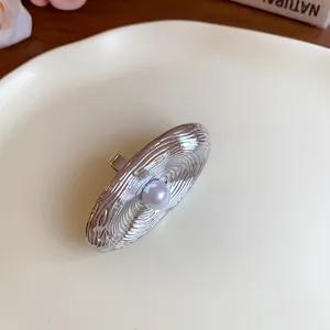 Vista dettagliata di orecchini ovali geometrici in argento con inserto di perla centrale