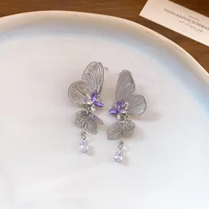 Detail of hollow butterfly earrings with purple crystals and teardrop tassel pendant