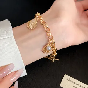 Vue détaillée d'un bracelet doré avec des éléments de coquillage et de perle au poignet