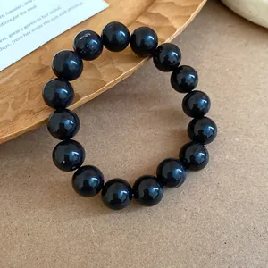 Detailed macro view of a polished black beaded bracelet displayed on a rustic wooden tray