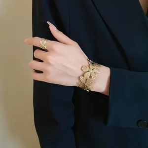 Detailed view of textured gold flower bracelet and matching ring on a hand model