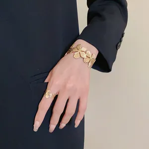 Detailed macro view of elegant gold-toned textured flower open cuff bracelet on wrist