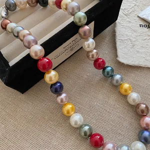 Close-up of vibrant multicolored pearl necklace on a velvet jewelry display tray.