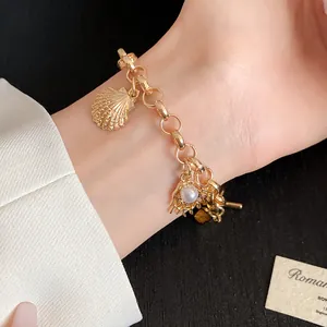 Vue détaillée des breloques en forme de coquillage doré et perle sur un bracelet marin