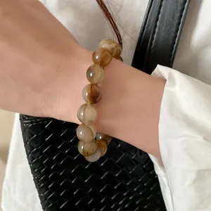 Detailed view of vintage amber swirl beaded bracelet worn on wrist with elegant outfit