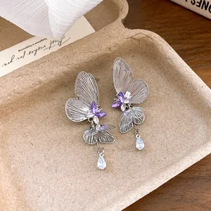 Detailed view of hollow butterfly earrings with purple crystals and teardrop pendants.
